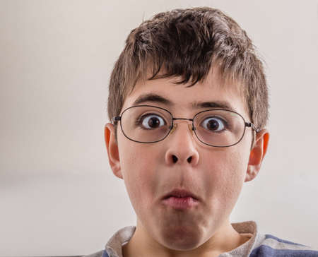 Boy sucks cheeks and  squeezes his lips making weird face as a sign of surpriseの写真素材