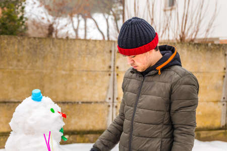 boy building  snowman with Plastic Accessories in a cold winter dayの写真素材