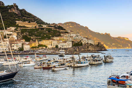 AMALFI (SA). ITALY - AUGUST 30, 2018: tourists are relaxing on boats moored in Amalfi marina at sunset
