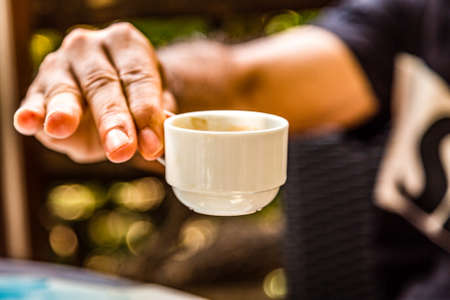 male hand holding a small cup of Neapolitan espresso coffeeの写真素材