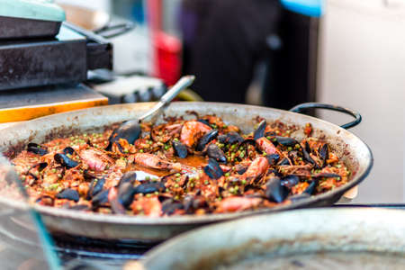 Mussels and shrimps in tomato sauce and peas cooked in pan in street market in Italyの写真素材