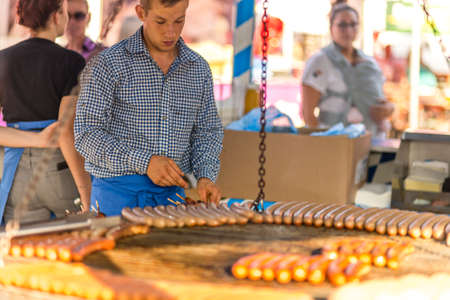 CERVIA (RA), ITALY - SEPTEMBER 16, 2018: Man cooking Sausages and bread on grill according to Bavarian cuisine at European Market, street exhibition of typical products from Europeのeditorial素材