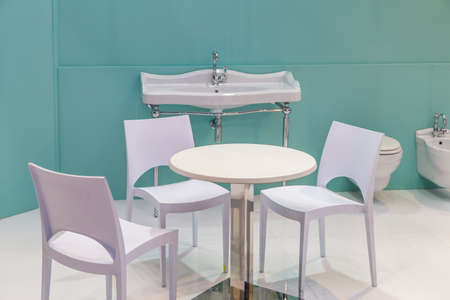 table and chairs in a bathroom with sink, bidet and toilet bowlのeditorial素材