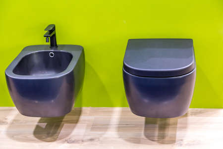 suspended blue toilet bowl and bidet on green wallのeditorial素材