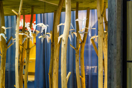 Paper origami in the shape of birds dangling from the ceiling among wooden sticksのeditorial素材