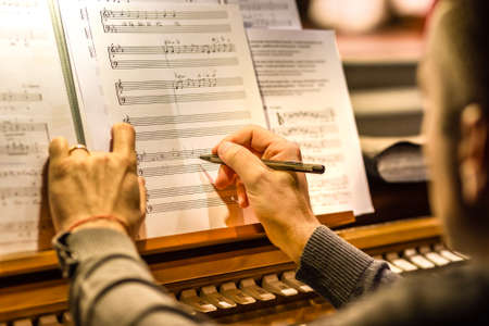 male hand writing music on white music sheet