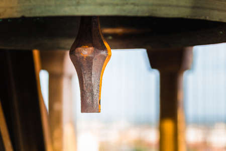 Clapper of ancient bronze bell with cityscape in backgroundの写真素材