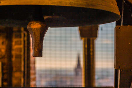 Clapper of ancient bronze bell with cityscape in backgroundの写真素材