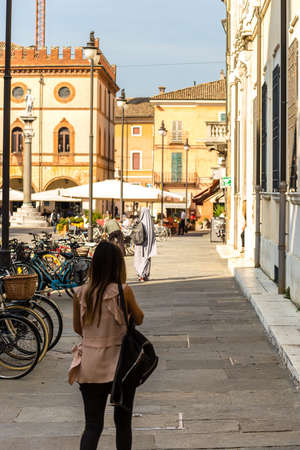 RAVENNA, ITALY: girl wearing abaya dress and walking in Piazza del Popolo, main square of the historical centerの写真素材