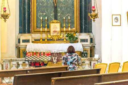 Kneeling woman praying in front of the altar of a Catholic Churchのeditorial素材