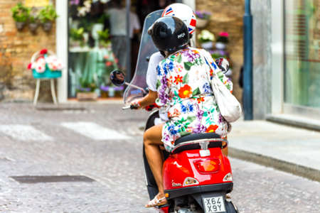 RAVENNA, ITALY - SEPTEMBER 13, 2018: girls riding Vespa, Italian scooter in street of historical centerのeditorial素材