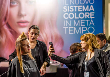 BOLOGNA, ITALY - NOVEMBER 25, 2018:  Hairstylist performs hairstyle in a stand.のeditorial素材