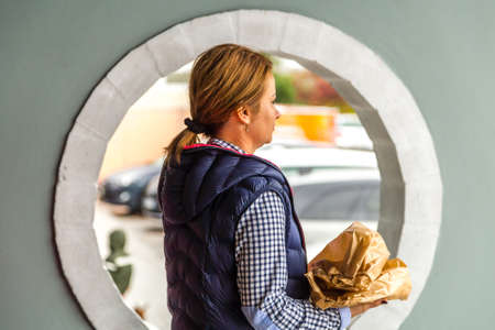 TRIESTE, ITALY - NOVEMBER 2, 2018: woman with bread going out from shop of highway service station