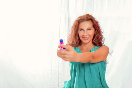 woman with long hair smiling and pointing spray bottle. Caucasian but with Middle Eastern or Indian...