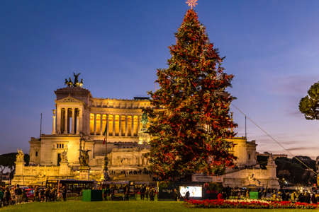 ROME, ITALY - JANUARY 1, 2019: tourists walking near Altar of the Fatherland while cars are passing and lights are shining on Christmas tree in Piazza Veneziaのeditorial素材