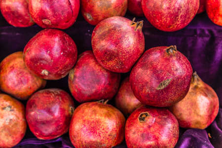 Group of fresh red pomegranates for sale in market stallの写真素材