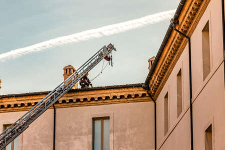 RAVENNA, ITALY - JANUARY 15, 2019: A brave firefighter checks the damage caused by the earthquake and removes the dangerous roof tiles from the State Historical Archives buildingのeditorial素材