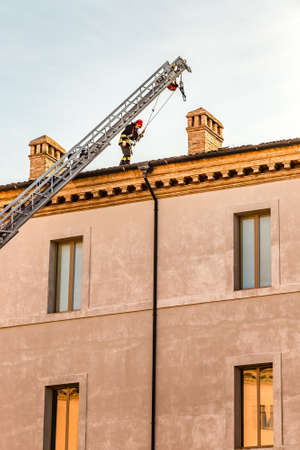 RAVENNA, ITALY - JANUARY 15, 2019: A brave firefighter checks the damage caused by the earthquake and removes the dangerous roof tiles from the State Historical Archives buildingのeditorial素材