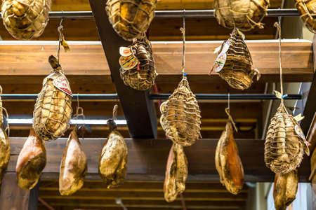 BOLOGNA, ITALY - DECEMBER 16, 2018: lights are enlightening hanged hams, pepperoni and culatello  at...
