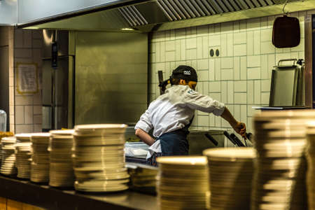 BOLOGNA, ITALY - DECEMBER 16, 2018: female cook cooking in restaurant kitchen at FICO Eataly World, the largest gourmet agri-food park in the worldのeditorial素材