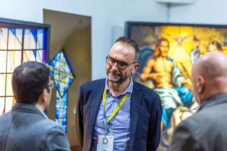 BOLOGNA, ITALY - FEBRUARY 18, 2019: Booth presenter talking with visitor at stand of VITRUM ARTE in...