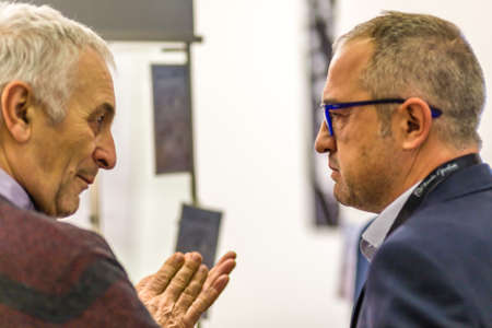 BOLOGNA, ITALY - FEBRUARY 18, 2019: Booth presenter talking with visitor at stand of ANGELO AREZZO...