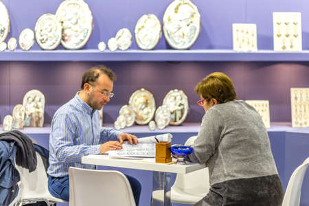 BOLOGNA, ITALY - FEBRUARY 18, 2019: booth presenter talking with visitor at stand of ASA in DEVOTIO...