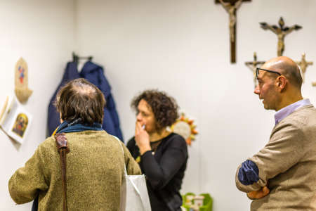 BOLOGNA, ITALY - FEBRUARY 18, 2019: booth presenter talking with visitor at stand of ANGELI in...