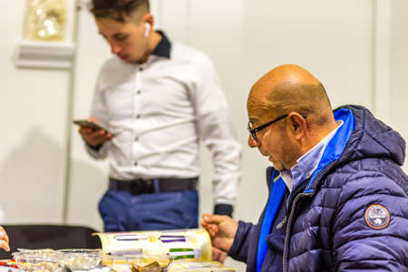 BOLOGNA, ITALY - FEBRUARY 18, 2019: booth presenter talking with visitor at stand of DOMUS in...