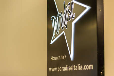 BOLOGNA, ITALY - FEBRUARY 18, 2019: lights are enlightening PARADISE logo on signboard on stand in...