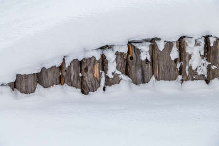 fence of weathered logs covered by snowの写真素材