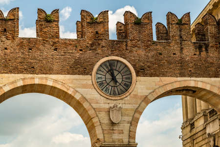 old clock placed on the top of the entrance city arched gate in Veronaの写真素材