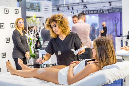 BOLOGNA (BO), ITALY - MARCH 18, 2019: exhibitor applying cosmetic treatment on model at COSMOPROF, trade show of the beauty industryのeditorial素材