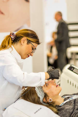 BOLOGNA (BO), ITALY - APRIL 12, 2019: artist applying cosmetic treatment on model at Cosmofarma Exhibition, the pharmacy worldâs leading Europeanのeditorial素材