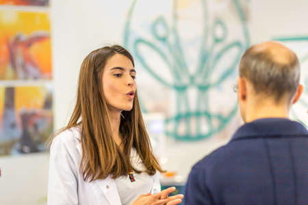 BOLOGNA (BO), ITALY - APRIL 12, 2019: exhibitor is welcoming visitor at Cosmofarma Exhibition, the pharmacy worldâs leading Europeanのeditorial素材
