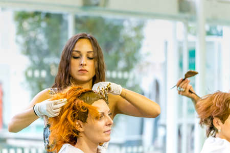 BOLOGNA (BO), ITALY - SEPTEMBER 6, 2019: exhibitor putting henna in hair of visitor at SANA 2019, 31st international exhibitionof organic and natural productsのeditorial素材