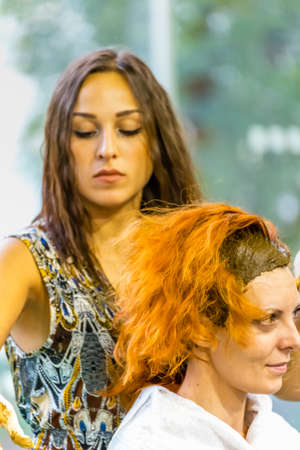 BOLOGNA (BO), ITALY - SEPTEMBER 6, 2019: exhibitor putting henna in hair of visitor at SANA 2019, 31st international exhibitionof organic and natural productsのeditorial素材