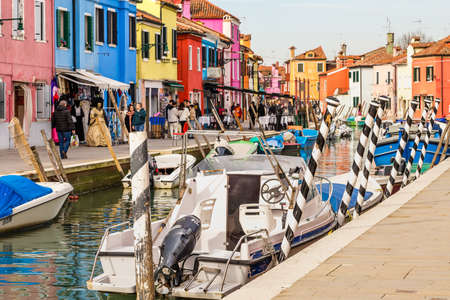 BURANO (VE), ITALY - FEBRUARY 21, 2020: tourists walking along the colorful houses of the ancient fishing village during Carnivalのeditorial素材