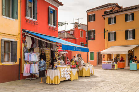 BURANO (VE), ITALY - FEBRUARY 21, 2020: people in shops are waiting for tourists walking in the typical square of Burano, ancient fishing village during Carnivalのeditorial素材