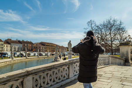 PADOVA, ITALY - FEBRUARY 23, 2019: tourist taking photos while people going for shopping in typical market in Prato della Valleのeditorial素材