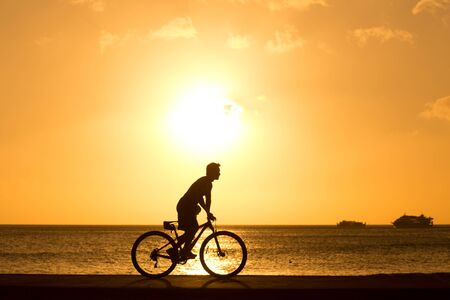 man ride bicycles outdoors against sunset. Silhouette. の写真素材