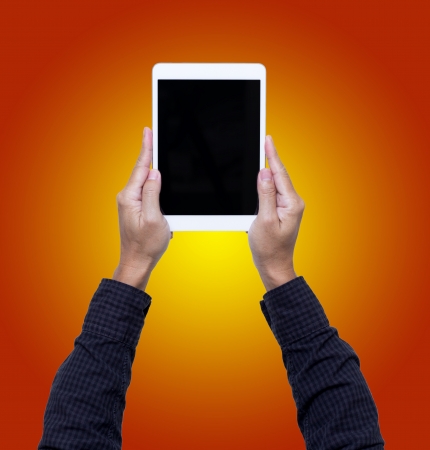 Man hands hold digital tablet isolated on orange backgroundの写真素材