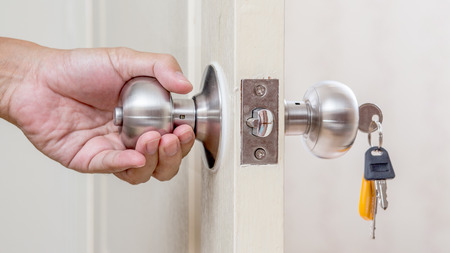 Hand holding door knob with keysの写真素材