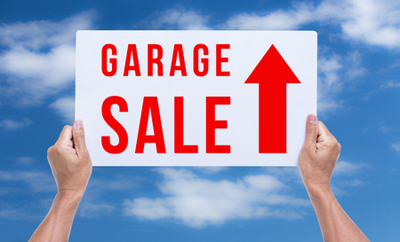 Two hands holding brown cardboard with garage sale on blue sky backgroundの写真素材