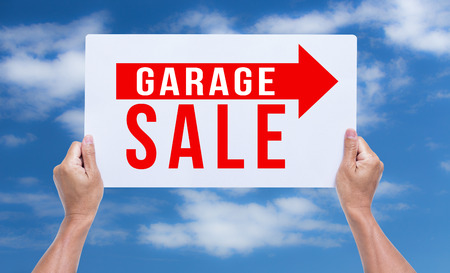 Two hands holding brown cardboard with garage sale on blue sky backgroundの写真素材