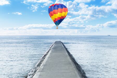 Old pathway into the sea with hot air balloon overの写真素材