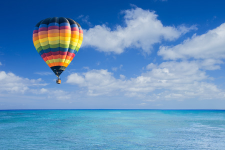 Colorful hot air balloon fly over the blue seaの写真素材