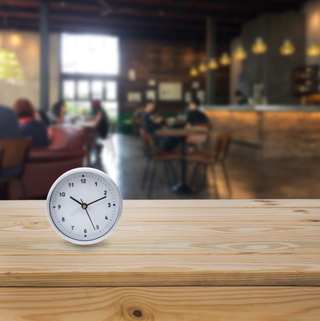 Circle clock on wood table with blue coffee shop backgroundの写真素材