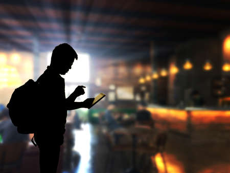 Silhouette man using tablet computer with blue coffee shop backgroundの写真素材