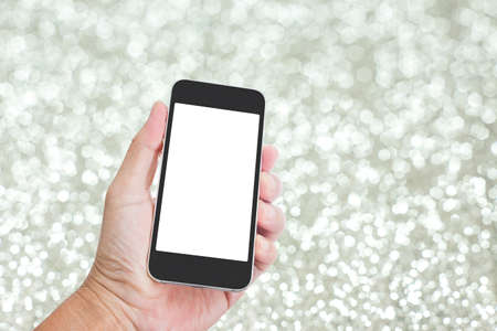Hand holding mobile phone with festive silver glitter background